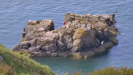 Friends-roam-rocky-island-cliff-outcrop-in-Howth-Ireland,-irish-sea