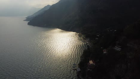 Sun-reflects-off-misty-mountainous-Lake-Atitlan-at-Jaibalito-Guatemala