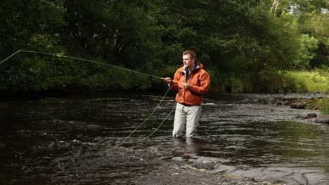 Hand-held-shot-of-a-fly-fisherman-wading-and-casting-into-slow-sections-of-a-stream
