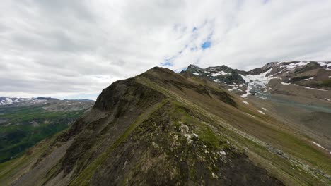 Vuelo-De-Drones-Sobre-Una-Afilada-Cresta-Montañosa-Austriaca-Con-Picos-Cubiertos-De-Nieve-Visibles-En-La-Distancia