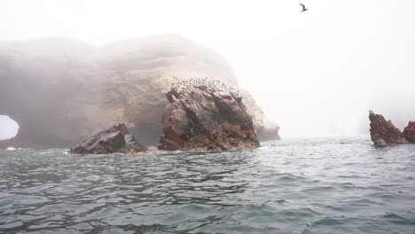 Cinematic-Shot-Of-Huge-Rocks-Formation-In-Foggy-Weather-In-The-Pacific-Ocean-In-Paracas-National-Reserve,-Ica-Peru