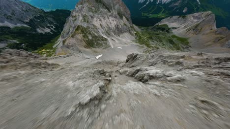 FPV-drone-dive-down-a-steep-mountain,-overseeing-the-valley-in-Tyrol-region-of-Austria