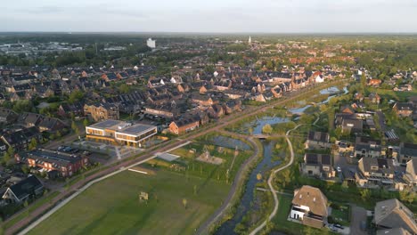Drone-shot-of-a-residential-area-of-the-city-of-Nijkerk-in-the-Netherlands-with-a-nature-park-at-sunset