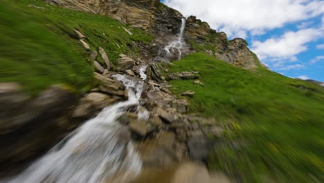 FPV-drone-flying-at-close-range-of-a-mountain-stream-and-waterfalls-near-the-Grossglockner-alpine-road-in-Austria