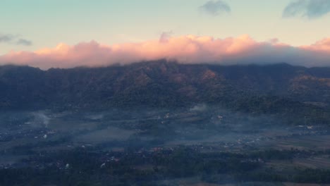 Aerial-view-of-indonesian-countryise-in-foggy-morning-with-mountain-range-on-the-background