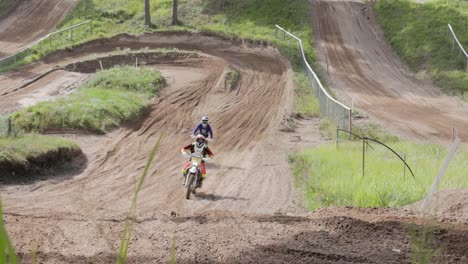 A-pair-of-enduro-riders-cruising-around-a-motocross-track-on-their-off-road-motorbikes-on-a-beautiful-summers-day-in-Europe