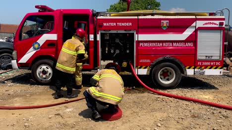 Indonesische-Feuerwehrleute-Verpacken-Ausrüstung-In-Feuerwehrauto.-Seitenansicht,-Zeitlupe