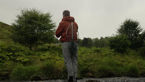 Hand-held-shot-of-a-fly-fisherman-casting-into-a-river-in-Scotland