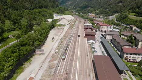 Aerial-View-Of-Train-on-Train-Tracks-in-the-middle-of-green-tall-mountains