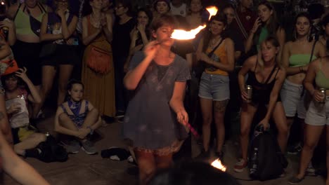 Una-Mujer-Actúa-Con-Un-Poi-De-Fuego-Balanceándose-Durante-Un-Evento-Público,-Mujeres-Y-Niños-Observan-Reunidos-En-Círculo