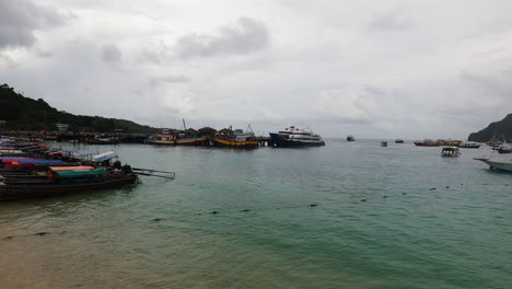 Phi-Phi-township-bay-with-moored-boats,-handheld-pan-left-view