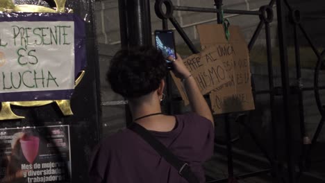 Argentinian-non-binary-teenager-takes-pictures,-records-feminist-protest-signs-with-smartphone-near-National-Congress-facade