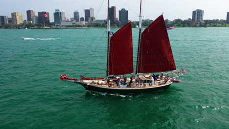 Aerial-view-away-from-a-tall-ship,-sailing-in-front-of-the-Windsor-skyline-in-sunny-Canada