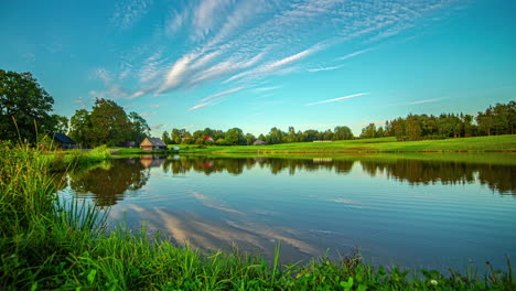 A-Time-Lapse-Shot-Of-A-Wind-Shear-And-A-Small-Village-In-A-Green-Landscape-By-The-Lake