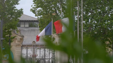 Zeitlupe-Umkreisende-Aufnahme-Französischer-Flaggen,-Die-Im-Wind-Auf-Fahnenmasten-In-Narbonne-Wehen
