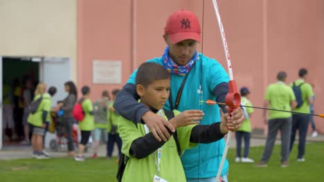 Toma-Manual-De-Un-Instructor-Enseñando-Tiro-Con-Arco-A-Un-Niño-En-El-Evento-Para-Discapacitados-De-Narbona.