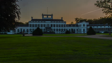 Beautiful-time-lapse-of-the-sun-setting-behind-a-imposing-palace-in-the-Netherlands,-the-camera-pans-from-left-to-right