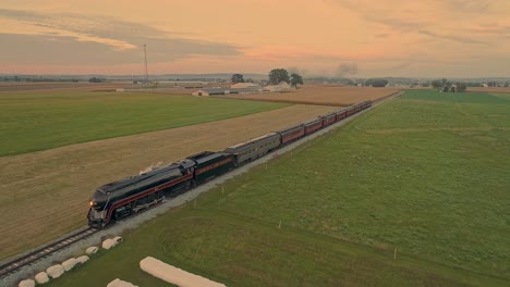 Aerial-View-following-a-Streamlined-Steam-Train-Traveling-Thru-Rural-Countryside-at-the-Golden-Hour