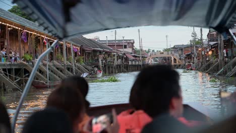 Casi-Al-Atardecer,-Un-Grupo-De-Turistas-Locales-Y-Extranjeros-Están-Haciendo-Un-Recorrido-Por-El-Mercado-Flotante-De-Amphawa-Mientras-Navegan-En-Un-Barco-De-Madera,-En-Samut-Songkhram,-Tailandia