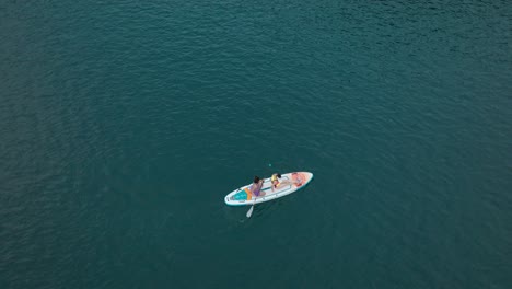 Zwei-Mädchen-Paddeln-Auf-Einem-Farbenfrohen-Sup-Board-über-Dem-Tiefblauen-See