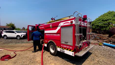 Toma-En-Cámara-Lenta-De-Un-Bombero-Con-Un-Camión-De-Bomberos-Indonesio-Durante-La-Operación-De-Extinción-De-Incendios-A-La-Luz-Del-Sol