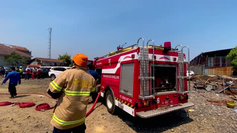 Primer-Plano-De-Un-Bombero-Indonesio-Con-Casco-Y-Manguera-En-Funcionamiento-Durante-Un-Incendio-En-Una-Casa-Durante-El-Día---Magelang,-Indonesia