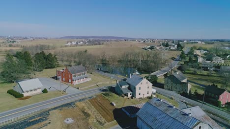 Eine-Drohnenansicht-Einer-Amish-Landschaft-Mit-Einem-Bach,-Einem-Wasserfall,-Einer-Mühle-Und-Bauernhöfen-Im-Winter