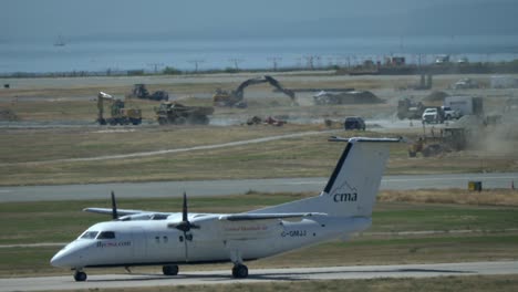 De-Havilland-Canada-Dash-8-Despegando,-Obras-En-Curso-En-El-Aeropuerto-Al-Fondo