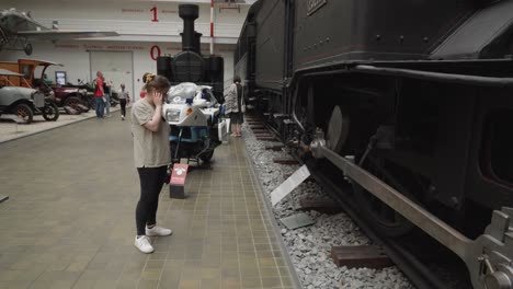 Frau-Beobachtet-Alte,-Historische-Lokomotive,-Ausgestellt-Im-Nationalen-Technischen-Museum-In-Prag,-Tschechische-Republik