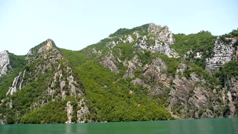 Albania,-Lago-Koman,-Vista-Desde-Un-Ferry-En-Movimiento-De-Las-Verdes-Laderas-De-Las-Montañas-Sobre-El-Agua