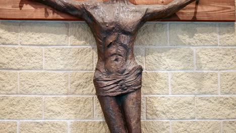 Braune-Metallskulptur-Der-Kreuzigung-Jesu-Christi,-Die-An-Der-Kirchenwand-Hängt