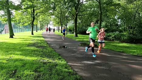 Slow-motion-athletic-group-of-people-running-in-charity-marathon-in-shaded-public-park