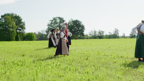 People-in-traditional-Swedish-costumes-walking-on-a-field-during-a-midsummer-celebration