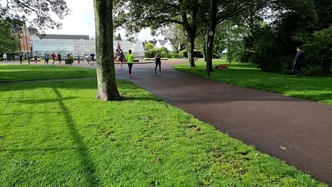 Slow-motion-group-of-people-running-in-charity-marathon-in-shaded-public-park