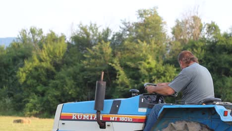 Farmer-drives-tractor-loaded-with-hay-bales-summer-agricultural-activity