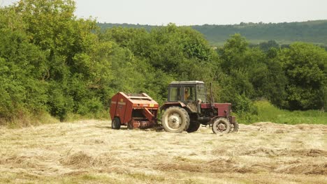 Happy-tractor-driver-waves-to-camera-as-he-makes-hay-bales-during-harvest