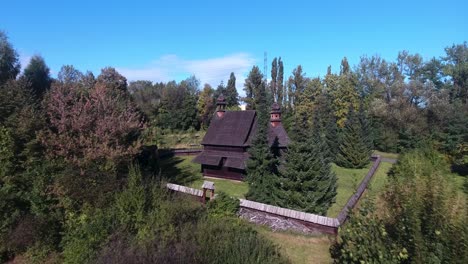 Eine-Historische-Holzkirche,-Die-Während-Der-Sommersaison-Von-Einem-Zaun-In-Einem-Europäischen-Freilichtmuseum-Umgeben-Ist