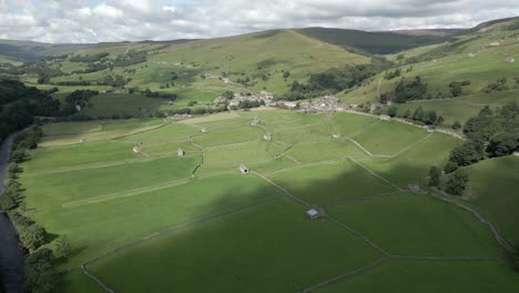 An-aerial-view-of-the-Yorkshire-village-of-Gunnerside-and-the-surrounding-Yorkshire-Dales-on-a-sunny-summer-day,-England,-UK