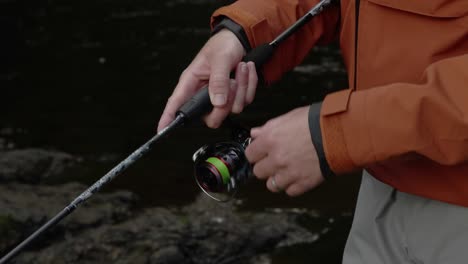 Slow-motion-shot-of-a-fisherman-using-a-spinning-rod-and-reeling-in-slowly