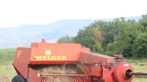 Agricultural-machinery-gathers-harvest-hay-in-rural-countryside-scene