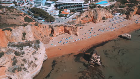People-walking-on-the-beach-during-the-summer-in-Praia-Dona-Ana-in-the-Algarve-in-Portugal,-aerial-drone-view