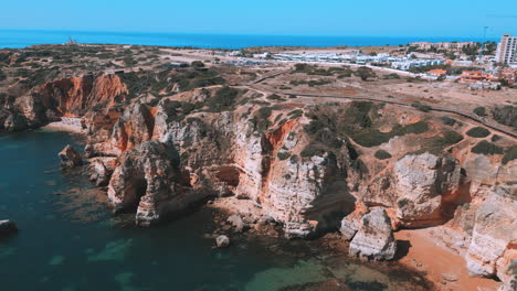 Rocky-cliffs-and-beautiful-blue-ocean-during-the-summer-in-Praia-Dona-Ana-in-the-Algarve-in-Portugal,-aerial-drone-view