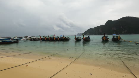 Famous-touristic-Thai-excursion-boat-lands-on,-cloudy-day-on-Koh-Phi-Phi-island