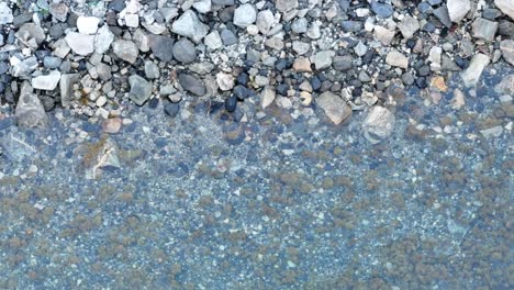 Pebbles-Under-Clear-Water-Of-A-Lake-In-Gryllefjord,-Senja,-Norway---top-view