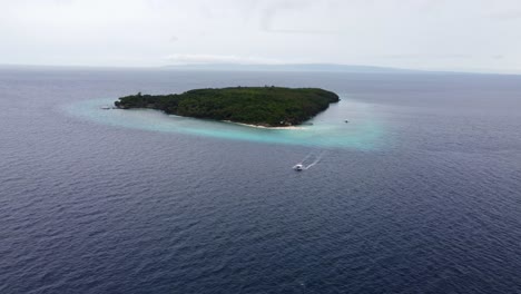 Aerial-drone-view-of-Sumilon-island,-with-a-tourist-filipino-banca-Boat-passing-by,-a-small-island-in-open-sea-with-white-sandbar-beach-off-the-shore-of-oslob-in-Cebu-philippines