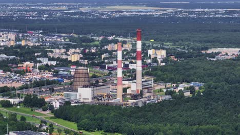 An-aerial-view-factory-with-two-high-chimneys-stands-on-the-outskirts-of-the-city-near-the-forest-on-a-sunny-summer-day