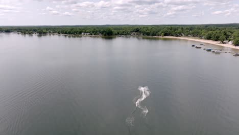 Jet-Ski-in-Lake-Missaukee-in-Lake-City,-Michigan-moving-with-drone-video-following-behind