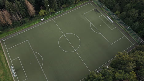 Luftaufnahme-Nach-Unten-über-Einem-Idyllischen,-Leeren,-Grünen-Fußballfeld-Mit-Toren-Und-Wald-Drumherum,-Drohnenaufnahmen