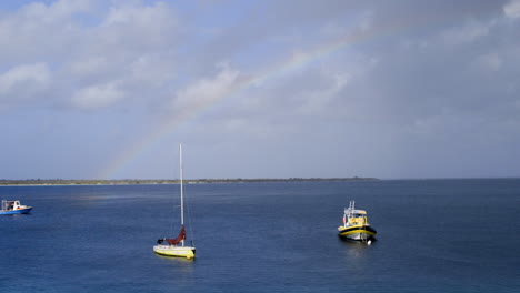 Boats-with-rainbow-in-Ocean-near-coast-of-Bonaire,-the-Caribbean,-the-Antilles