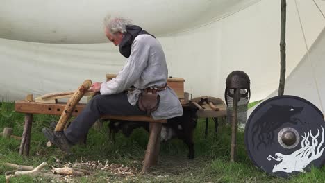 Recreación-Vikinga-De-Un-Trabajador-De-La-Madera-Con-Ropa-De-época,-Elaborando-Madera-En-Un-Implemento-En-Woodstown,-Waterford,-Irlanda